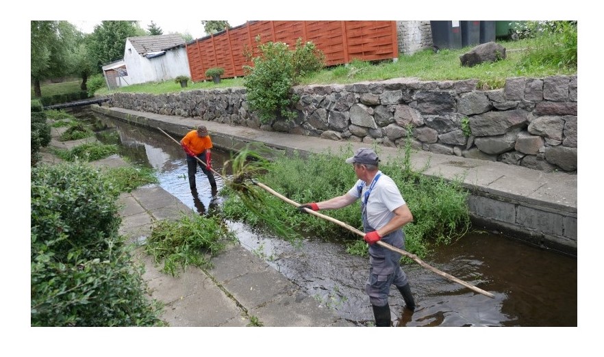 Dwóch pracowników czyszczących koryto rzeki Gesiej w miejscowości Barwice.