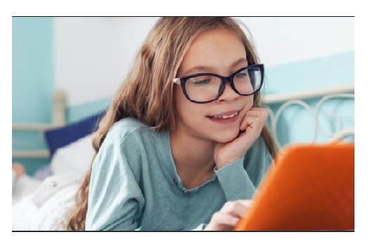 Uśmiechnięta dziewczynka w okularach korzystająca z komputera