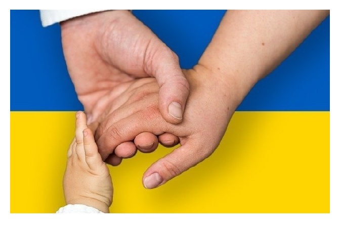Dłonie dziecka, kobiety i mężczyzny na tle ukraińskiej flagi 