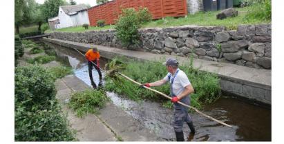 Dwóch pracowników czyszczących koryto rzeki Gesiej w miejscowości Barwice.